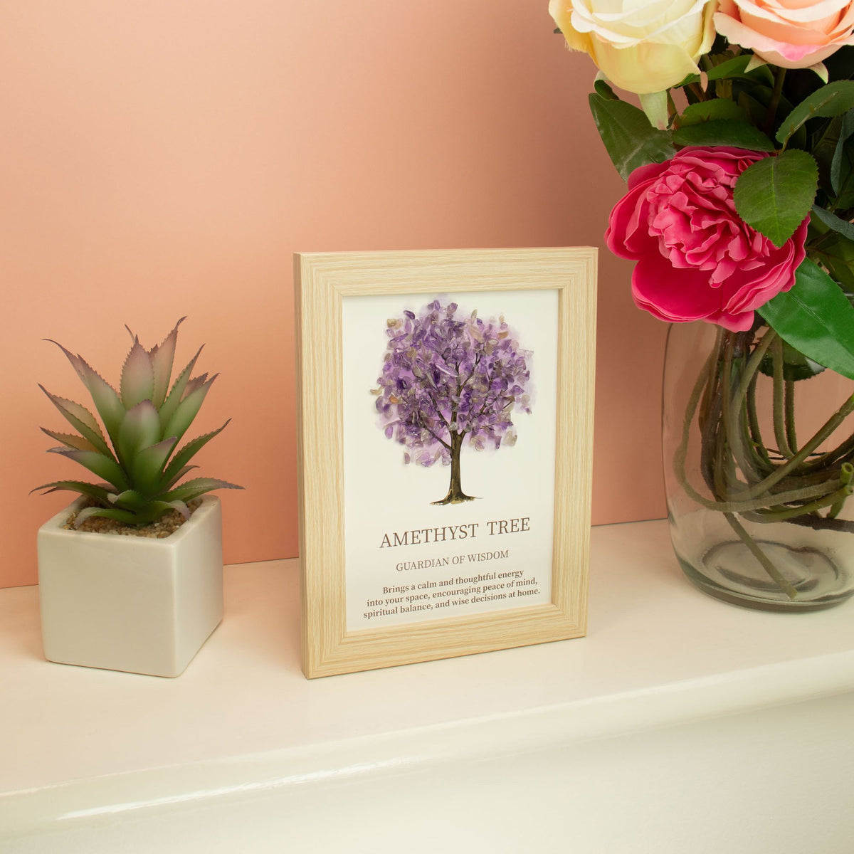 Das stilvolle Edelsteinbild Lebensbaum dekoriert auf einem weißen Board neben einer Sukkulente und bunten Blumen.