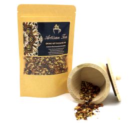 Bio-Chai-Tee Hot Chocolate von AW Artisan Tea im Standbeutel mit verschütteten Teeblättern vor weißem Hintergrund